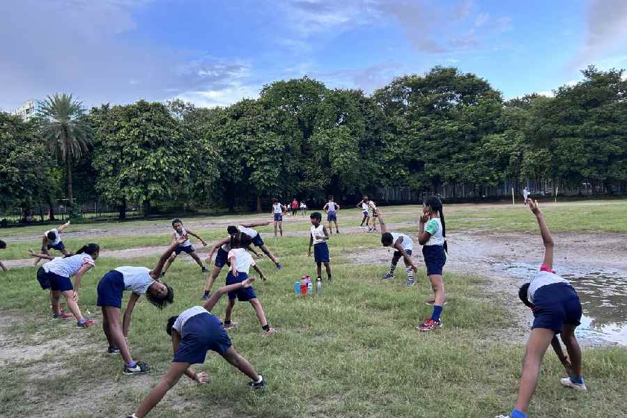 A group of younger boys kick up dirt and swing from poles on the edge of the green expanse. The coach’s whistle pierces the air. The group disperses with a flurry of movements and laughter