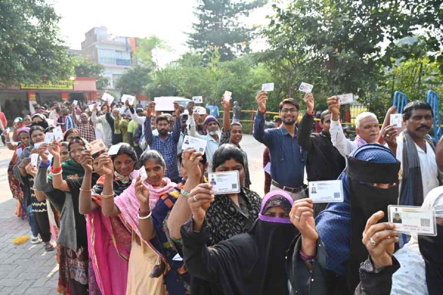 People show their ID cards as they wait in queues to cast their votes at a polling station during the second and final phase of the Bihar Assembly elections, in Gaya, Tuesday, Nov. 11, 2025.