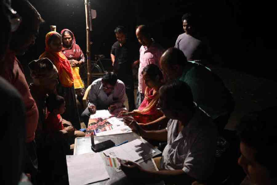 Residents and volunteers fill enumeration forms for the SIR on the volleyball court in the North 24-Parganas village on November 10. Picture by Bishwarup Dutta
