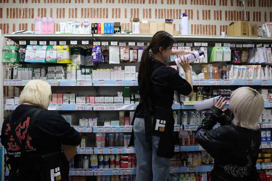 Hinako Mori, who dyed her hair, and her colleagues arrange products at a store of Japanese retailer Don Quijote in Tokyo, Japan, October 8, 2025.