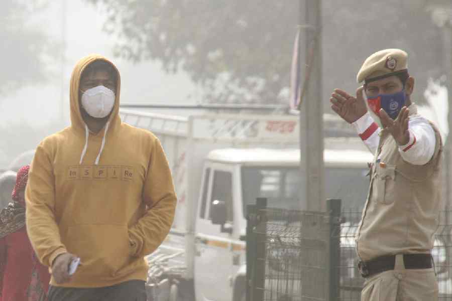 A pedestrian and a traffic policeman wear masks as air quality continues to deteriorate in Delhi-NCR, in Gurugram, Thursday, Nov. 13, 2025. Delhi's air quality remained in the 'severe' category for the third consecutive day, according to officials.