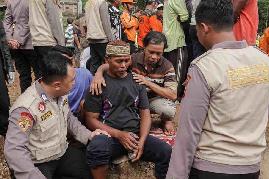 Relatives of victims react at the site of a landslide after it hit Cibeunying village, in Cilacap