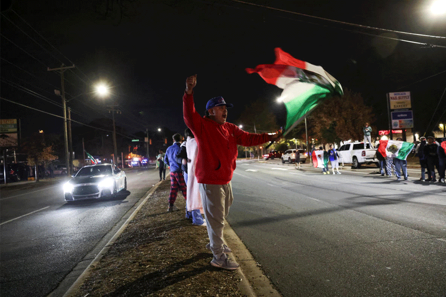 A demonstrator waves a Mexican flag as he participates in a protest, after federal authorities conducted raids, expanding their crackdown on illegal immigration, in Charlotte, North Carolina, U.S., November 17, 2025.