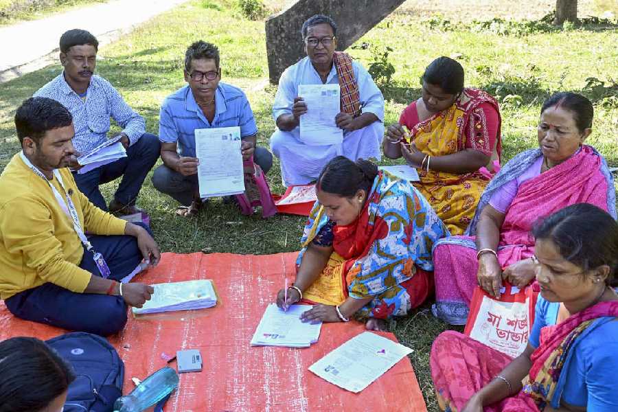 A Booth Level Officer (BLO) oversees the filling of enumeration forms by voters for the special intensive revision (SIR) of electoral rolls, in Malda district, West Bengal, Tuesday, Nov. 18, 2025