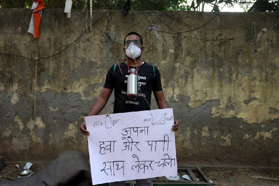 Harish Monsoon, 25, a demonstrator, poses for a photograph during a protest demanding government to take immediate steps to control air pollution in New Delhi, India November 18, 2025. The placard reads "Carry your own air and water".