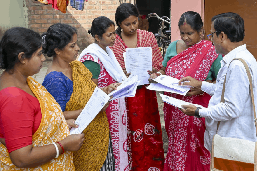A booth level officer (BLO) explains the details of enumeration forms to voters as the Special Intensive Revision (SIR) of electoral rolls begins in West Bengal, in Nadia, West Bengal, Tuesday, Nov. 4, 2025.