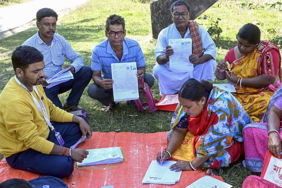 A Booth Level Officer (BLO) oversees the filling of enumeration forms by voters for the special intensive revision (SIR) of electoral rolls, in Malda district, West Bengal, Tuesday, Nov. 18, 2025.