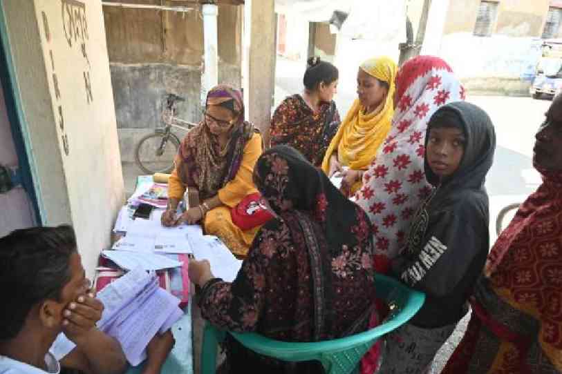 Voters fill out enumeration forms outside a saloon in Burdwan’s Goda on Thursday. Picture by Munshi Muklesur Rahaman