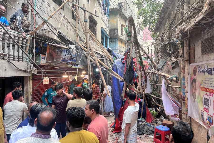 Residents stand in an alley after vacating their house next to a fallen scaffolding following an earthquake in Dhaka, Bangladesh, November 21, 2025.