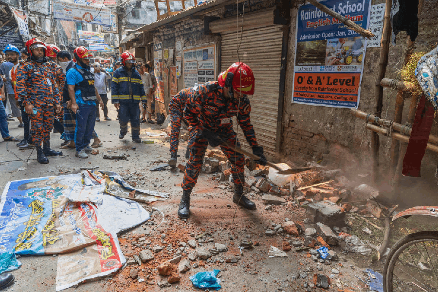 A rescue official clears the debris from roof and wall collapse after an earthquake in Dhaka, Bangladesh, Friday, Nov. 21, 2025.