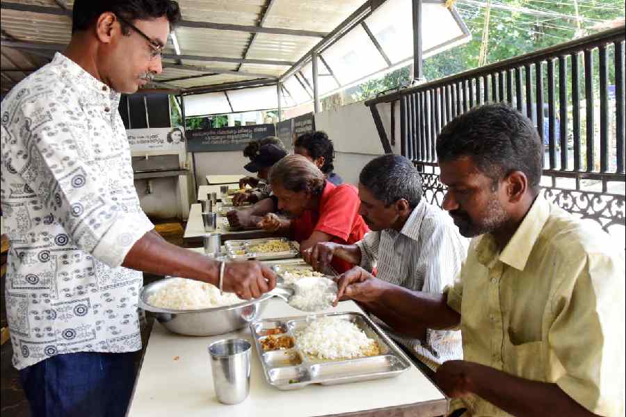 A volunteer serves food to people being distributed by the FACE Foundation at a food donation center, in Kochi, Kerala, Saturday, Nov. 1, 2025.