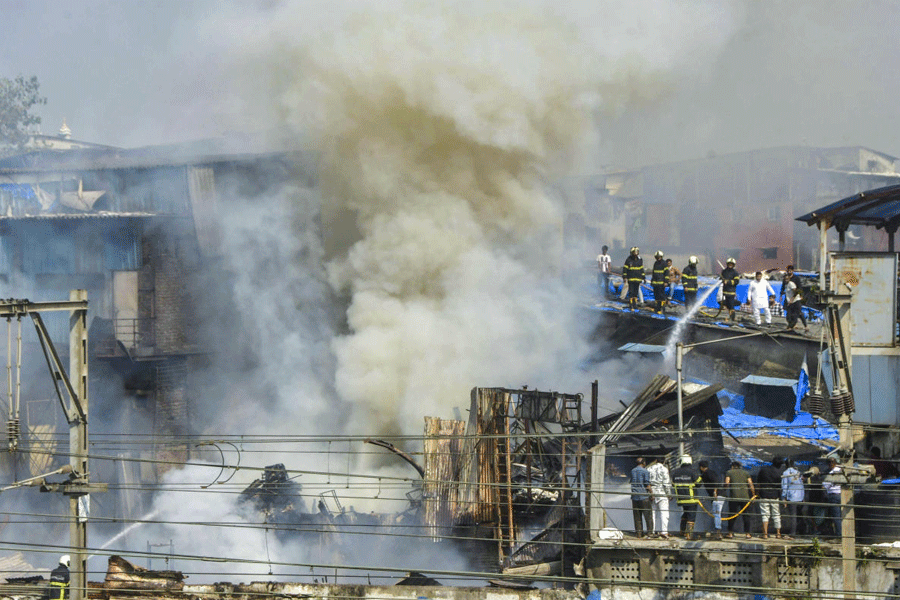 Smoke billows as firemen douse a fire breaking out in huts close to the Harbour line local train tracks at Dharavi area, in Mumbai, Maharashtra, Saturday, Nov. 22, 2025.