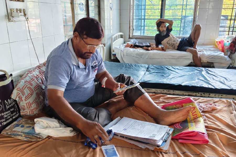 Mustafa Kamal, the BLO from Chopra block, uploads enumeration forms from his bed at the subdivisional hospital in Islampur on Saturday.
