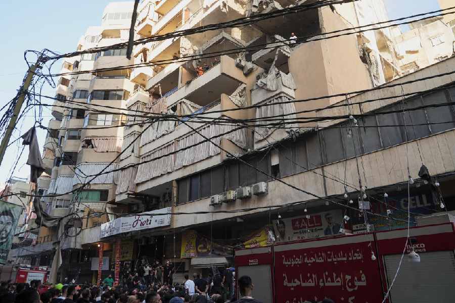 People gather near the site of an Israeli strike on a building, after Israeli military said on Sunday that it struck a militant from the Lebanese Iran-aligned Hezbollah group, in Beirut's southern suburbs