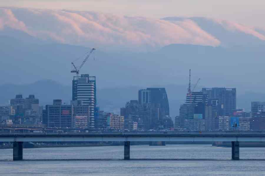 A view of the Taipei skyline with clouds hanging over distant mountains, seen from across the Tamsui River in Taipei, Taiwan, November 8, 2025.