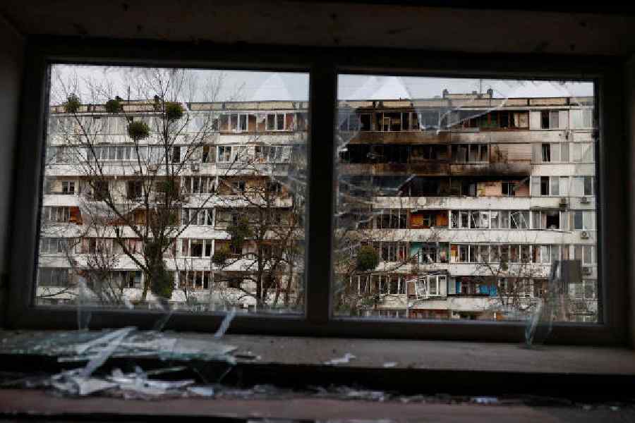 A building hit by a Russian drone strike is seen through a broken window in Kyiv on Tuesday.