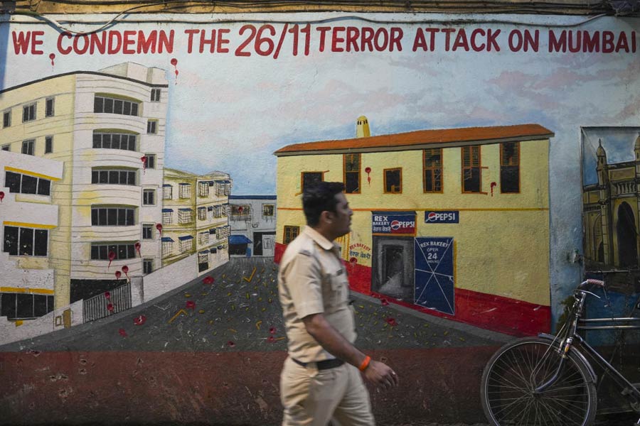 A police constable walks past a mural depicting Nariman House, one of the sites of the 2008 Mumbai terror attacks, on the eve of the anniversary of the gruesome incident, in Mumbai, Tuesday, Nov. 25, 2024.