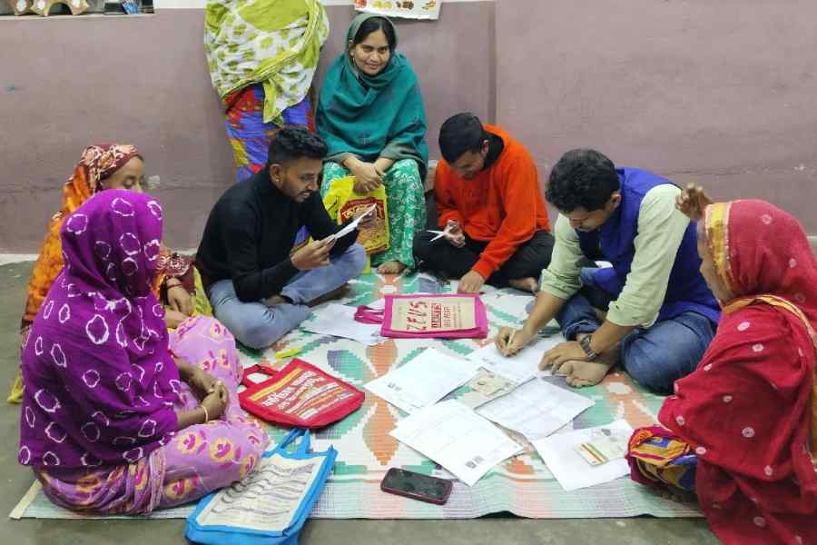 Members of a club in Santipur, Nadia, help Muslim women fill up SIR enumeration forms.