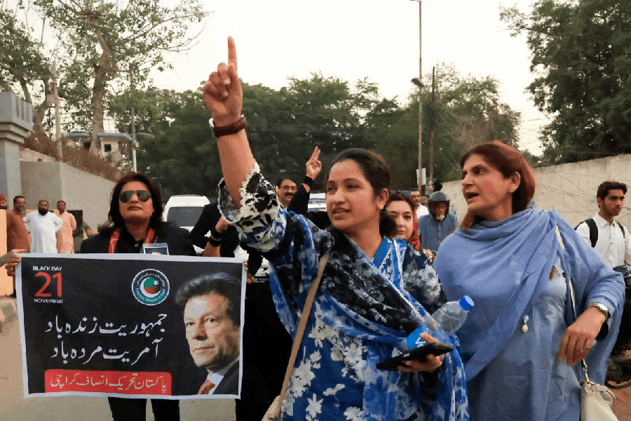 Supporters of former Prime Minister Imran Khan's party, the Pakistan Tehreek-e-Insaf (PTI), chant slogans while a placard is displayed as they observe 'Black Day' against what they call recent constitutional amendments, during an anti-government protest in Karachi, Pakistan, November 21, 2025.