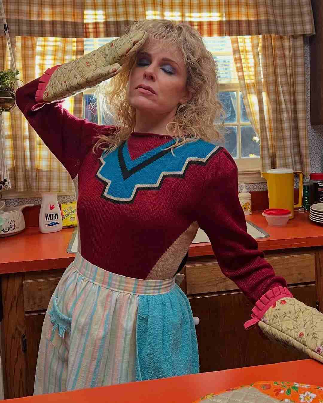 In another picture, Buonco wears a tired expression in a red sweater and beige oven mitts.  