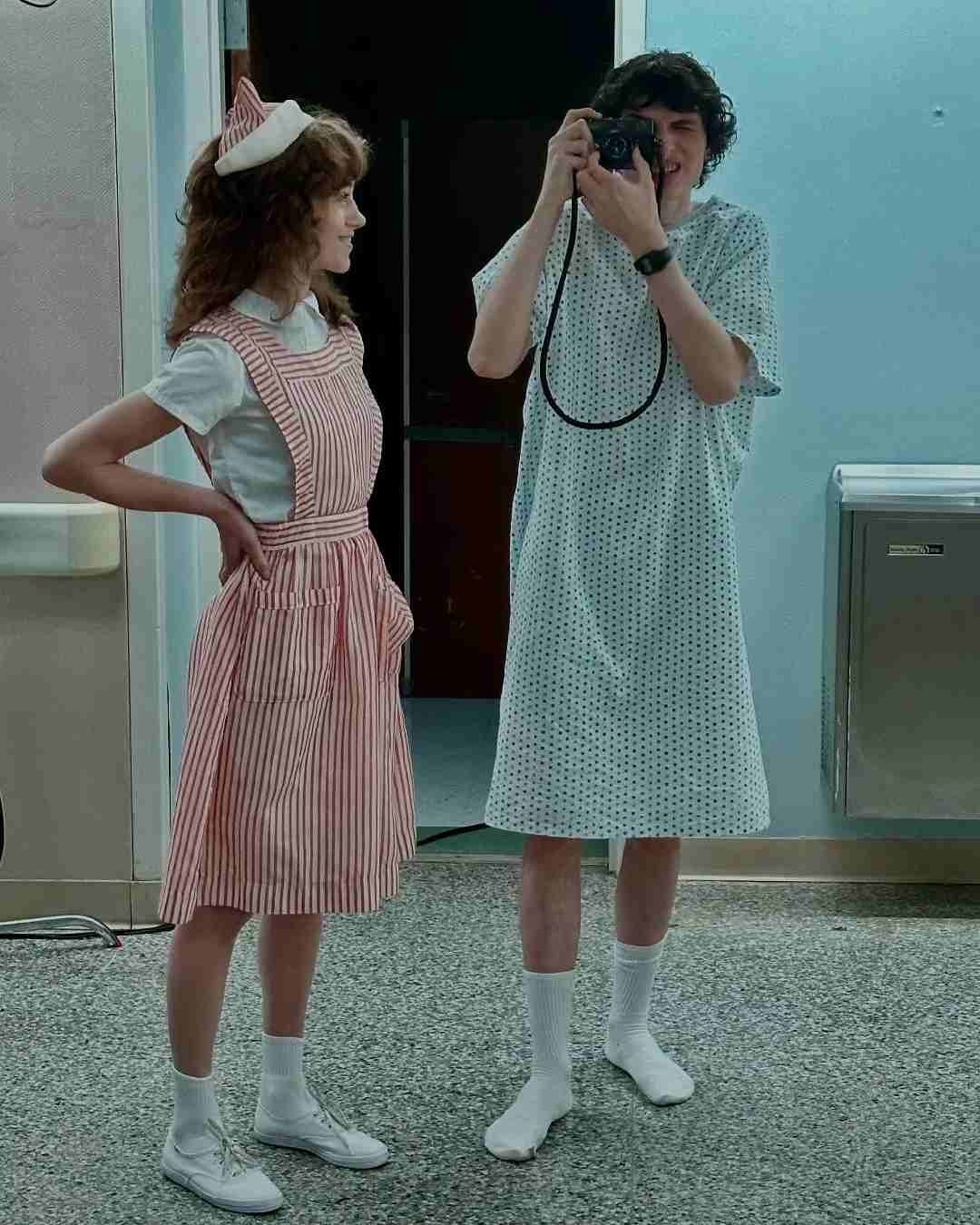 Natalia Dyer’s Nancy Wheeler looks at her brother Mike Wheeler (Finn Wolfhard) as he clicks pictures with a camera.  