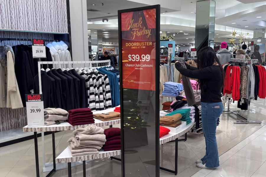 An employee folds clothes at a Macy's department store during Black Friday deals, a post Thanksgiving shopping frenzy that attracts throngs of bargain hunters to stores, at the Roosevelt Field mall in Garden City, New York, U.S., November 28, 2025.