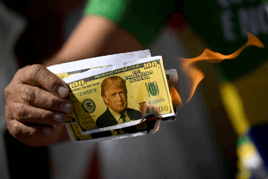 A demonstrator holds a burning mock dollar bills with the face of U.S. President Donald Trump during a protest against the tariffs on Brazilian products imposed by U.S. President Donald Trump, in front of the United States Embassy in Brasilia, Brazil.