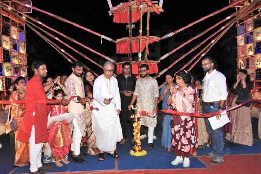 Former bureaucrat and former Rajya Sabha MP Jawhar Sircar cuts the ribbon to open the puja at CC Block in New Town as actor-physician Kinjal Nanda (in black) and CC Block secretary Biman Samaddar look on, along with others