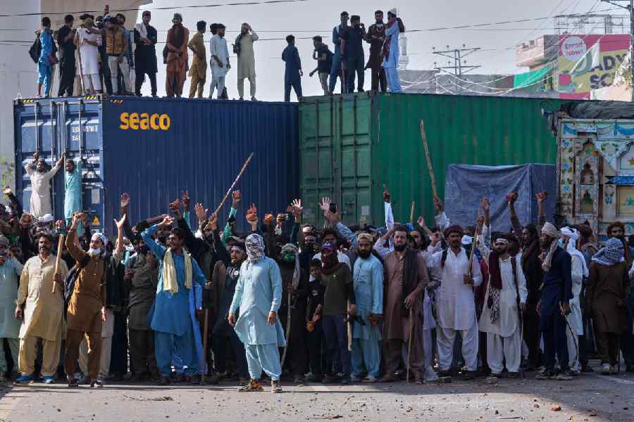 Supporters of Islamist party 'Tehreek-e-Labbaik Pakistan' chant religious slogans near their party's headquarters on a road barricaded with shipping containers by police to stop their pro-Palestinian march toward capital Islamabad, in Lahore, Pakistan, Friday, Oct. 10, 2025.