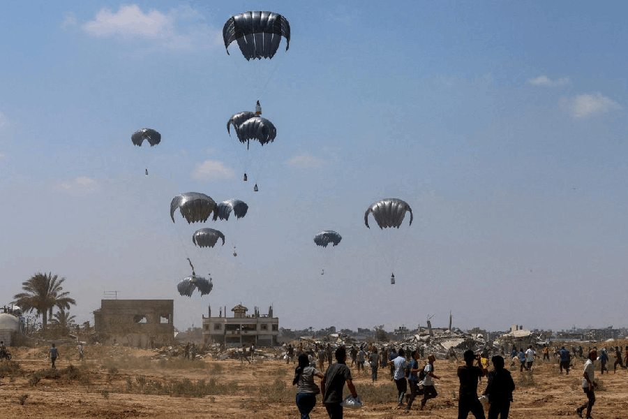 File photo: Palestinians run towards parachutes carrying aid packages, in Deir Al-Balah, in the central Gaza Strip.