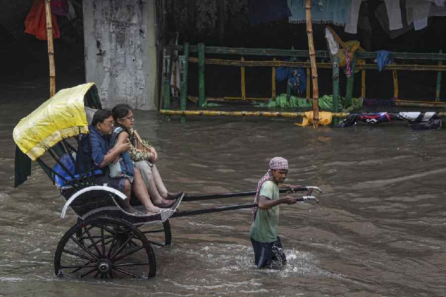 A rickshaw puller carries passengers through a waterlogged road following rain, in Kolkata, Tuesday, Sept. 23, 2025.