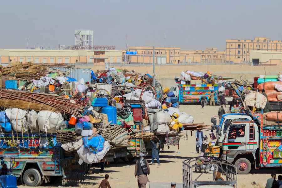 People walk past parked vehicles with belongings of Afghan citizens, as they head back to their country, after Pakistan closed border crossings with Afghanistan, following exchanges of fire between the forces of the two countries in Chaman