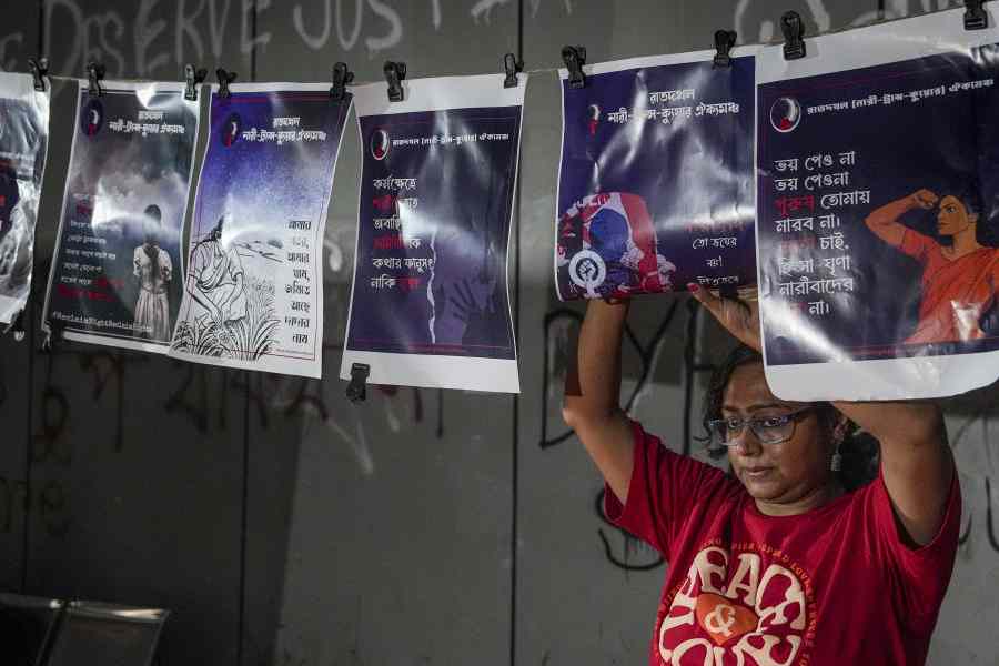 A woman hangs posters on a rope during a protest over the alleged rape of a medical student in Durgapur of West Bengal, in Kolkata,