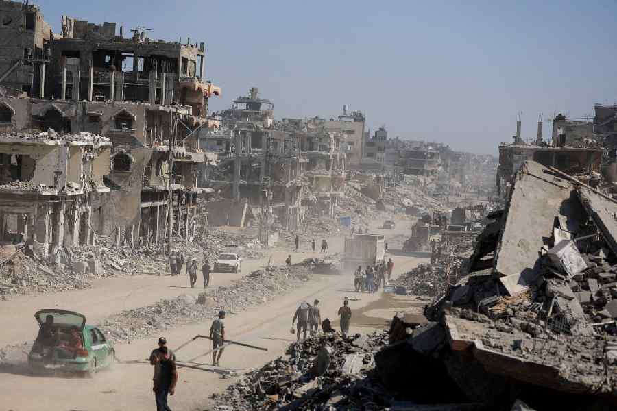 Palestinians walk past the rubble of destroyed buildings, amid a ceasefire between Israel and Hamas, in Gaza City, October 16, 2025.