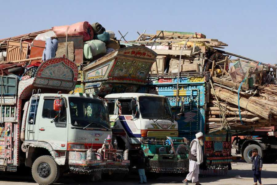 A man walks near children next to parked vehicles loaded with the belongings of Afghan citizens attempting to return to their country, after Pakistan closed border crossings with Afghanistan following exchanges of fire between the nations' forces, at the border crossing in Chaman, Balochistan Province, Pakistan October 16, 2025.