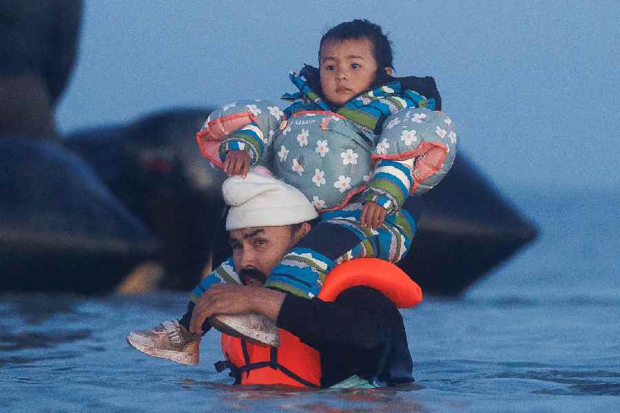 Migrants wait in the water for a 'taxi boat' to take them across the channel to the UK at dawn on September 19, 2025 in Gravelines, France.