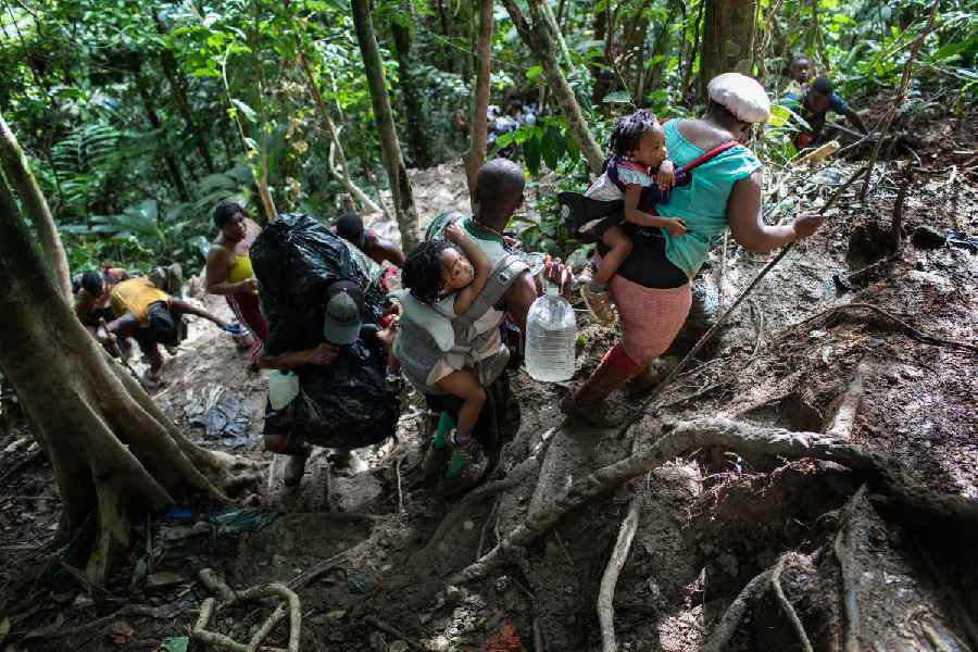 Immigrant families from Haiti climb a steep mountain trail near the border with Panama on the second day of their trek October 19, 2021 through the Darien Gap, Colombia.