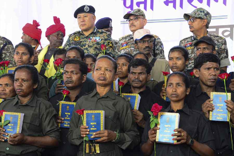 Naxalites hold copies of the Constitution of India after their surrender at the police lines, Jagdalpur, in Bastar district, Chhattisgarh, Friday, Oct. 17, 2025.