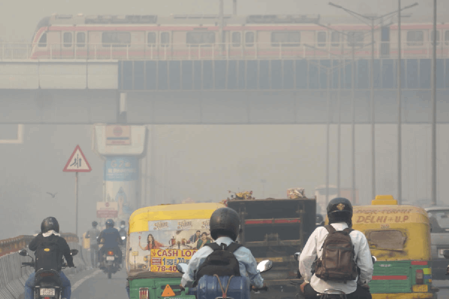 A metro train runs amid low visibility due to a layer of smog, near Ghazipur landfill in New Delhi, Saturday, Oct. 25, 2025.