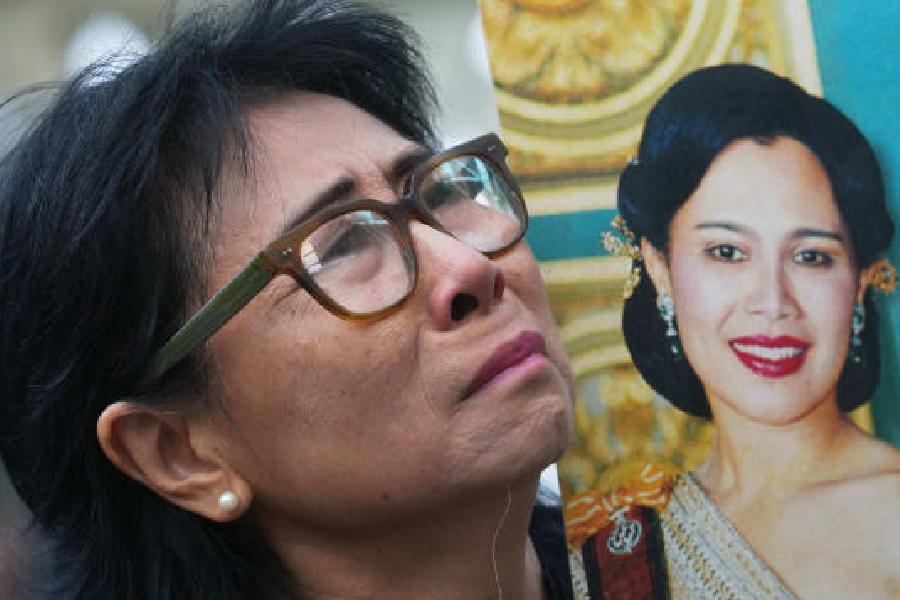 A woman mourns with a portrait of the queen in Bangkok on Saturday.