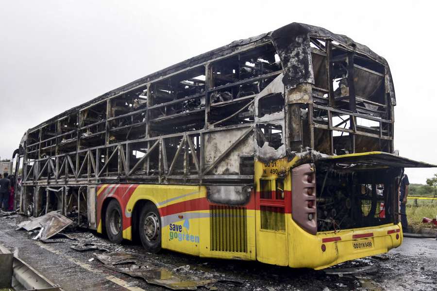 Kurnool: Police personnel investigate the spot where a Bengaluru-bound private bus caught fire after colliding with a two-wheeler, with the blaze being triggered after the motor bike with its fuel cap open was dragged underneath the bus, in Kurnool district, Andhra Pradesh, Friday, Oct. 24, 2025. At least 20 people were killed in the accident