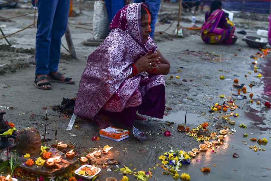 A woman offers prayers during the ‘Kharna Puja’ amid the 'Chhath Puja' festivities on the banks of the Ganga river at Sangam, in Prayagraj, Sunday, Oct. 26, 2025.