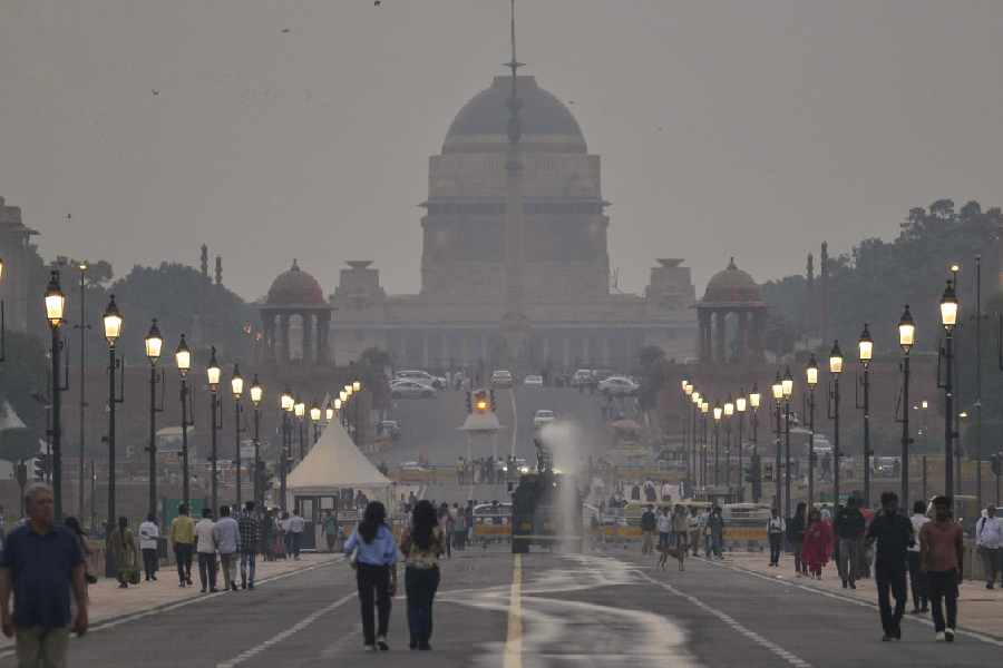 Visitors take a walk as an anti-smog gun sprays water along the Kartavya path overlooking the Rashtrapati Bhavan