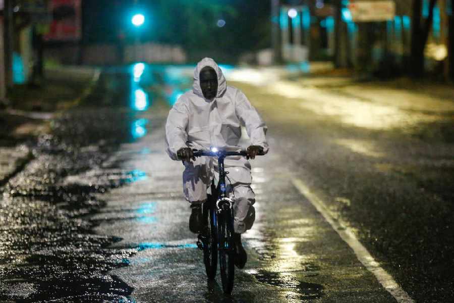 A man wearing a protective suit cycles on a street, as Hurricane Melissa approaches, in Kingston, Jamaica