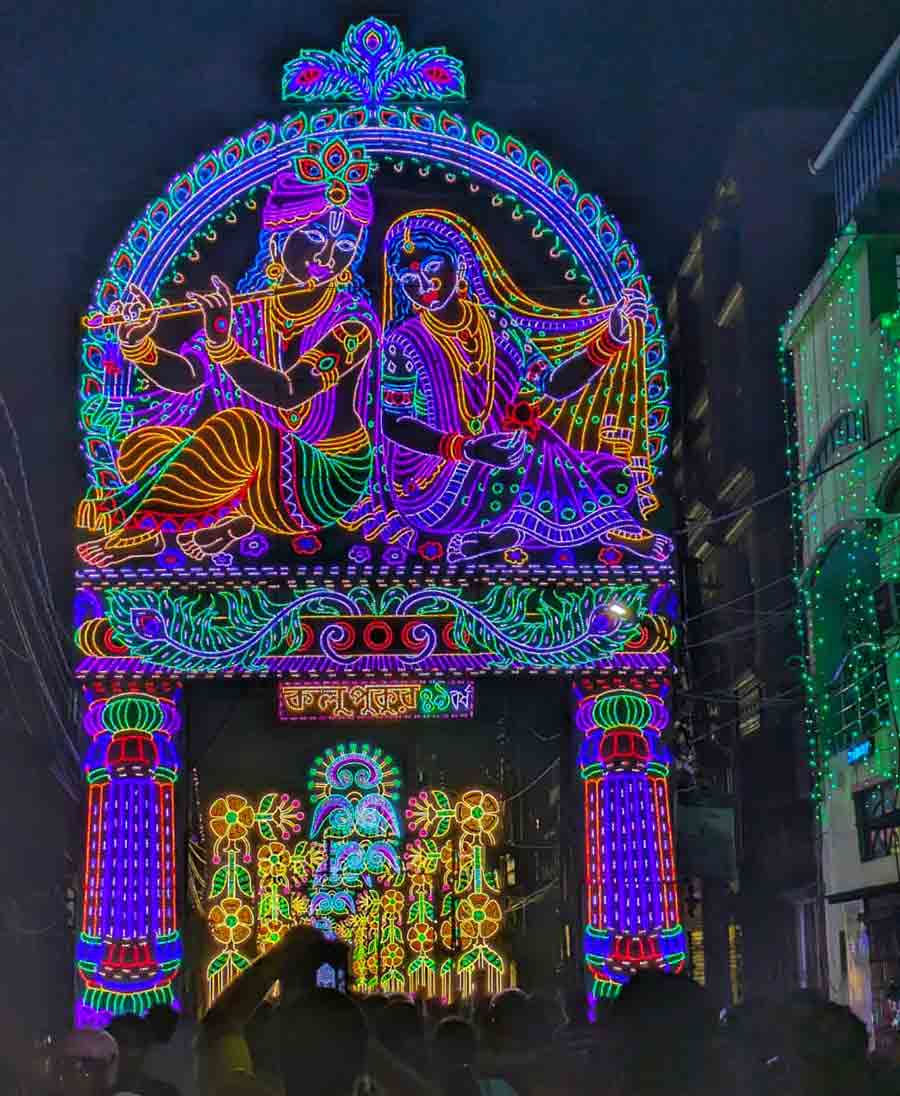 An archway of neon artistry depicting Radha and Krishna welcomes pandal-hoppers with colour and joy