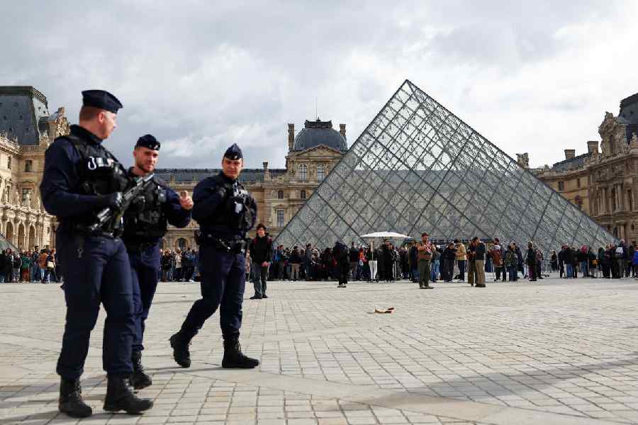 French CRS riot police officers walk near the glass Pyramid of the Louvre Museum, after French police arrested suspects in the Louvre heist case, in Paris, France October 27, 2025.