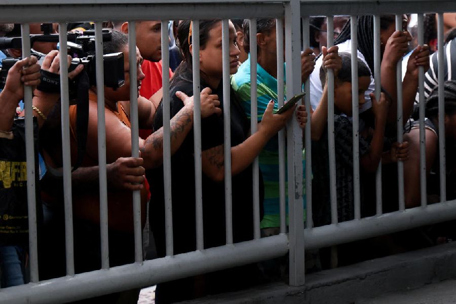People watch as the bodies of dead people are brought to a hospital, on the day of a police operation against drug trafficking at the favela do Penha, in Rio de Janeiro, Brazil