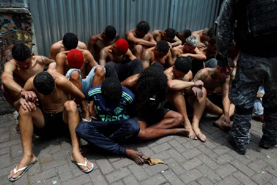Suspected drug dealers sit on the ground after they were detained by the military police, during a police operation in Rio de Janeiro