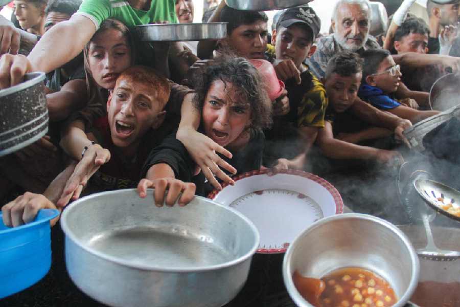 Palestinians gather to receive food cooked by a charity kitchen, amid the Israel-Hamas conflict September 11, 2024