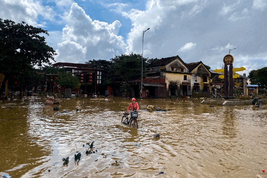 A woman with a cycle wades through a flooded street in Hoi An, following deadly floods in central Vietnam, October 31, 2025.